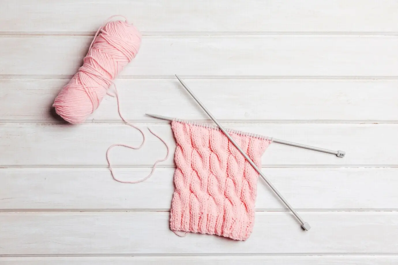 Pinkfarbene Wolle und Nadeln